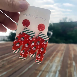 Detailed view of handmade Christmas glitter earrings with Santa and snowflake patterns
