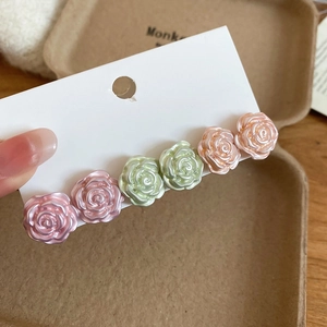 Detail of elegant resin hair clip featuring six pearlescent 3D roses in soft pastel colors