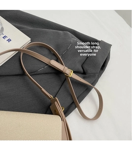 Detail of adjustable khaki leather strap and gold buckle on a beige woven shoulder bag