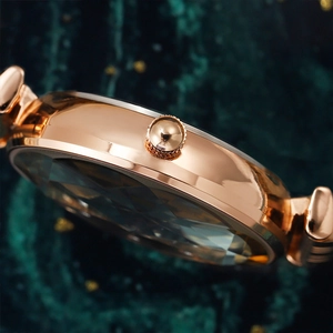 Side view of rose gold women's watch with faceted crystal glass and velvet background