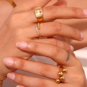 Close-up of a model wearing three 18K gold-plated rings with micro-set zircons and beads