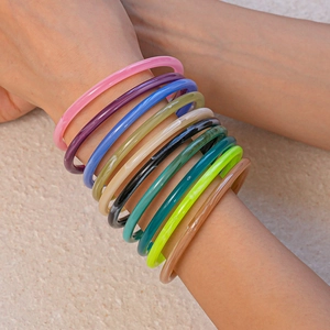 Close-up of colorful resin acrylic thin round bangles stacked on a female wrist