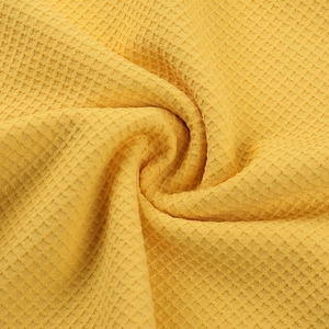 Vue macro détaillée de la texture du tissu en maille gaufrée jaune gingembre d'une robe