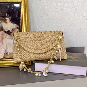 Detail of woven straw bag with golden chain, pearls, and natural seashells decoration