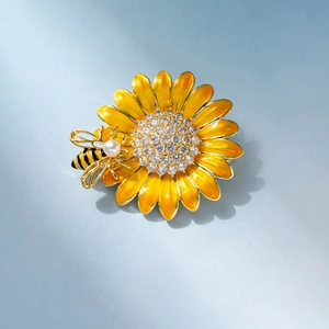 Detail of sunflower brooch with yellow enamel petals, sparkling zircons and a pearl bee