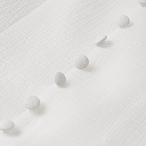 Detailed close-up of white seersucker fabric with elegant matching fabric-covered buttons
