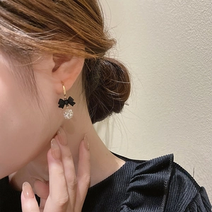 Close-up of model wearing vintage bow earrings with clear zircon ball drop charms
