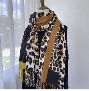Detail of leopard print scarf with fringe tassels in black, camel, and ginger tones