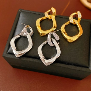 Dettaglio di orecchini a perno geometrici in oro e argento con zirconi scintillanti