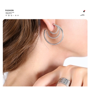 Detailed view of triple-layered hoop earrings and stacked ring in silver finish metal
