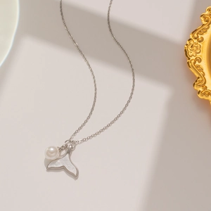 Detail of silver fishtail pendant with white pearl and shell inlay on delicate chain