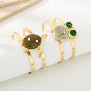 Golden owl and turtle open bangles with green gems and pearls on display stand
