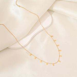 Elegant gold geometric necklace with square charms displayed on white textured fabric