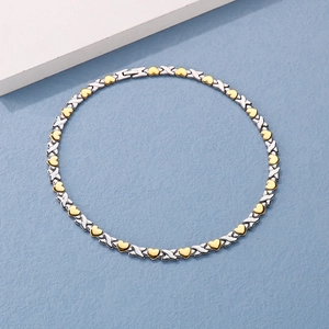 Detail of silver X-link and golden heart pattern necklace with a polished metallic finish
