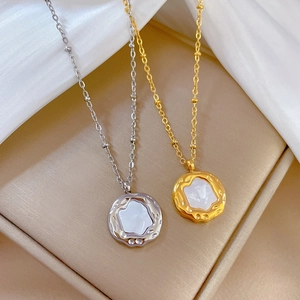 Close-up of gold and silver irregular shell necklaces on a beige jewelry tray