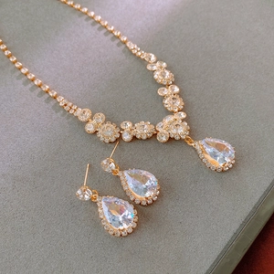 Dettaglio dell'elegante collana a goccia dorata e orecchini in cristallo coordinati