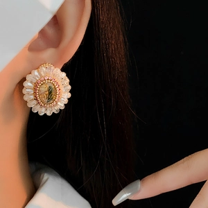 Detail view of crystal sunflower earrings with gold-tone accents on a model