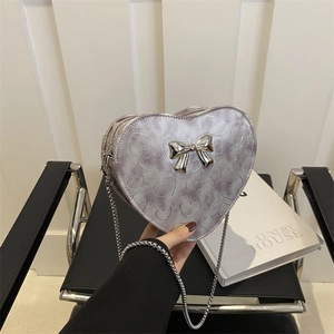 Silver heart-shaped crossbody bag with bow detail and metallic chain strap