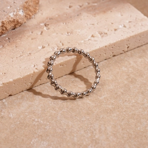 Detail of a silver wavy textured irregular metal ring on a minimalist stone background