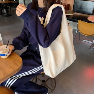 Minimalist cream canvas tote bag with large capacity shown in a lifestyle cafe setting