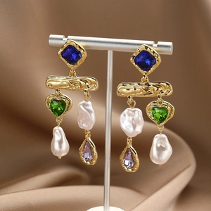 Detailed close-up of Baroque pearl earrings with multicolor crystals on silk fabric