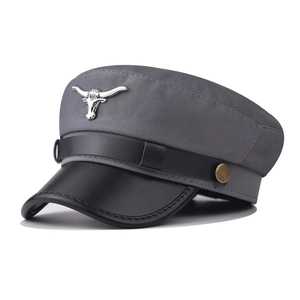 Close-up of military cap featuring grey wool fabric, black leather brim, and silver bull head badge