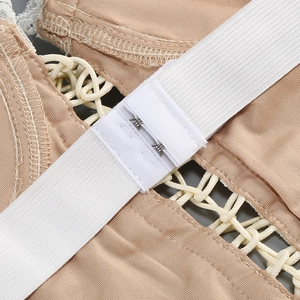 Detail of metal hook-and-eye closures on beige lace bodice with elastic straps
