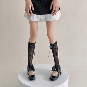 Close-up of black lace leg warmers with ribbon bows paired with Mary Jane shoes