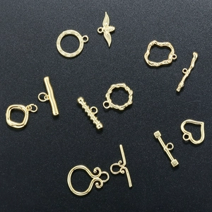 Detailed close-up of 18K gold plated OT clasps and heart charms on black background
