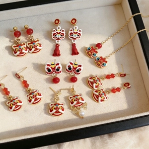 Detailed close-up of festive lion dance earrings with red tassels and pearls on tray