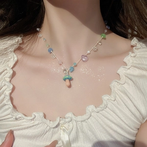 Detailed view of baroque pearl necklace with colorful beads and a small mushroom pendant