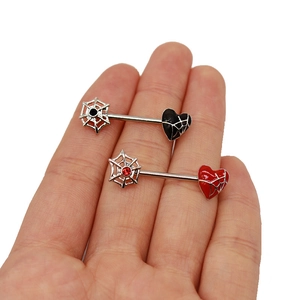 Detail of red and black heart-shaped nipple rings with spider web patterns on steel bars
