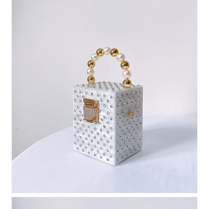 Macro view of white pearlescent acrylic box bag with rhinestones and pearl handle