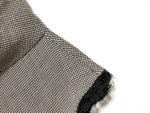 Detailed close-up of houndstooth fabric with delicate black floral lace embroidery