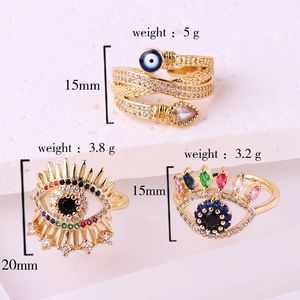 Macro detail of three gold evil eye rings featuring colorful crystals and snake patterns