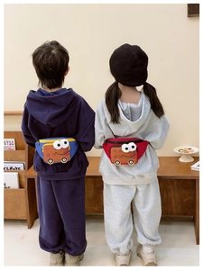 Children wearing red and blue cartoon bus waist bags with adjustable straps in a cozy setting