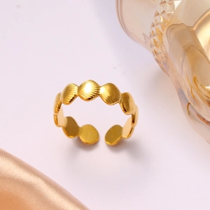 Close-up of golden seashell pattern open ring on elegant silk and glass background