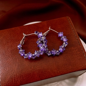 Detailed view of silver-tone hoop earrings with geometric purple zircon on leather