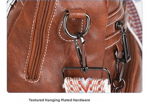Detail of vintage brown textured leather backpack with gunmetal D-ring and woven strap