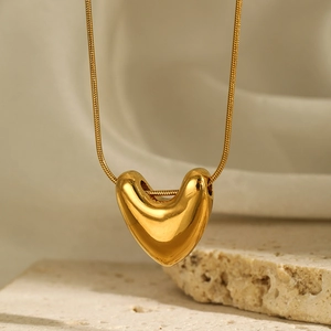 Detailed view of polished 3D gold heart pendant on a delicate snake chain necklace