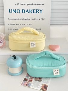Quilted smiley face makeup bag with handle in yellow and mint green colors