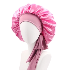 Detail of pink satin sleep bonnet with adjustable ribbon tie on white display stand