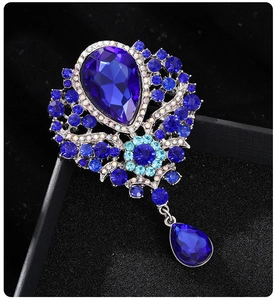 Detail of luxury royal blue crystal brooch with pear-shaped pendant on black display box