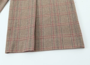 Close-up of the khaki houndstooth woven fabric and precision stitching of the blazer