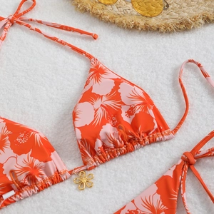 Detail of floral bikini top with bright hibiscus print and gold flower charm pendant