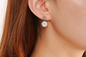 Close-up of silver titanium steel hoop earrings with Roman numerals and central crystal