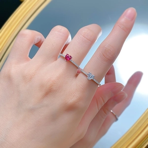 Detailed view of silver heart-shaped rings with red and clear stones on a mirror