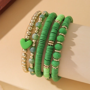 Detail of bohemian stackable bracelets with green clay beads and heart charms