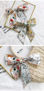 Detail of printed satin hair scarf with abstract face pattern styled on a straw bag