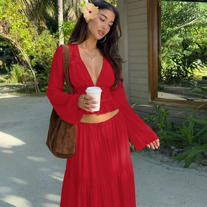 Detail of red two-piece chiffon set with deep V-neck top and flowy long skirt in tropical setting